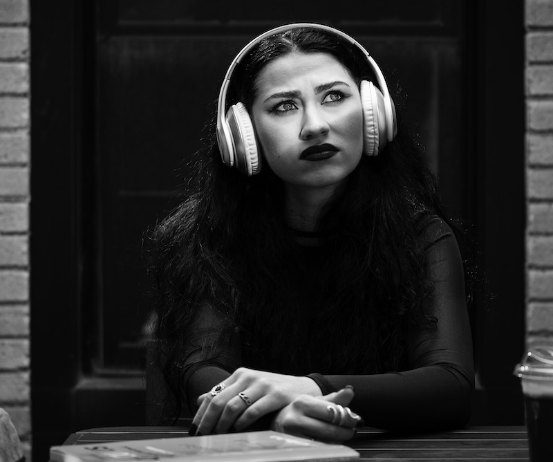 Young adult girl wearing headphones and looking to the right with thinking face expression