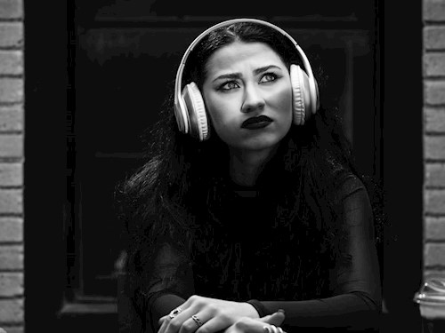 Young adult girl wearing headphones and looking to the right with thinking face expression