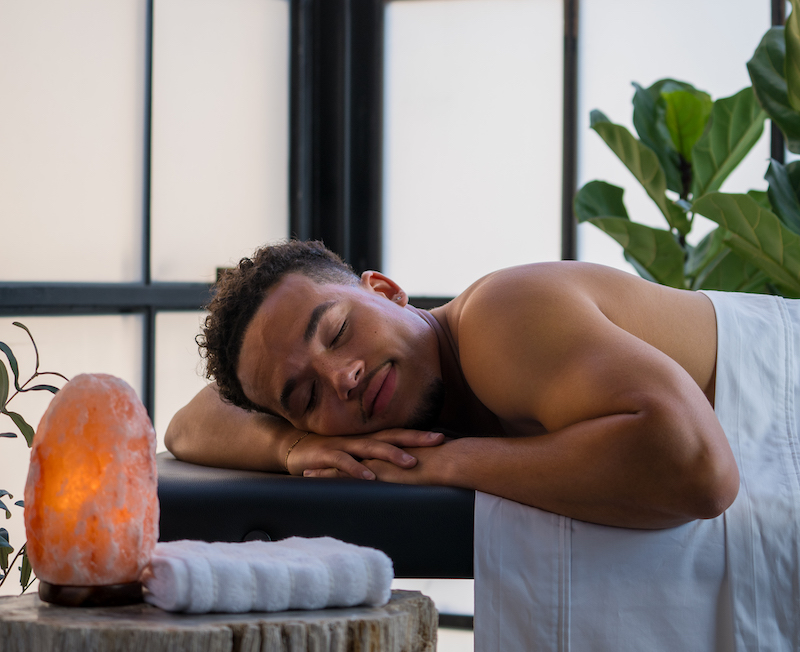 Male at the spa laying on a massage bed with his eyes close