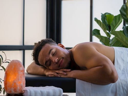 Male at the spa laying on a massage bed with his eyes close