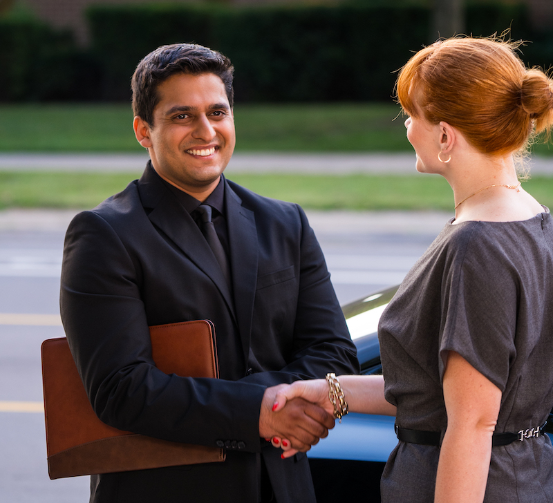 Male and woman are shaking hands in the parking lot