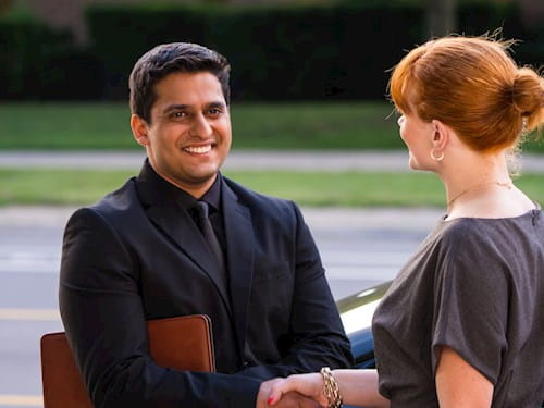 Male and woman are shaking hands in the parking lot