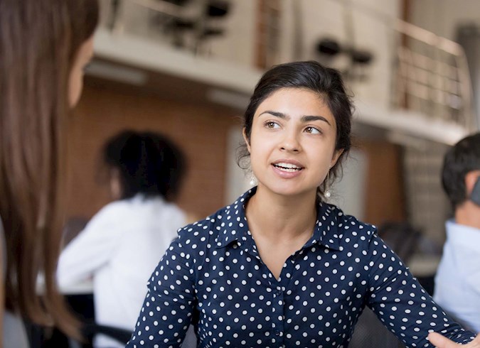 Attractive female Indian employee talking, discussing business strategy