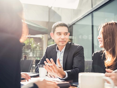Male in a meeting, discussing work with his team and client at a cafe