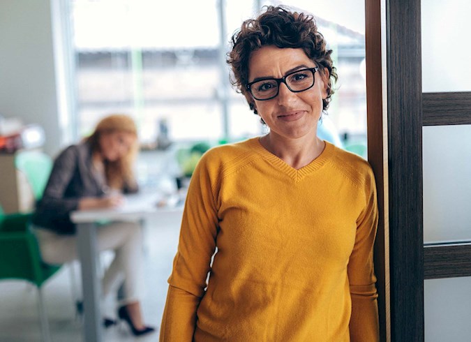 A lady in yellow sweater is facing the camera and smiling